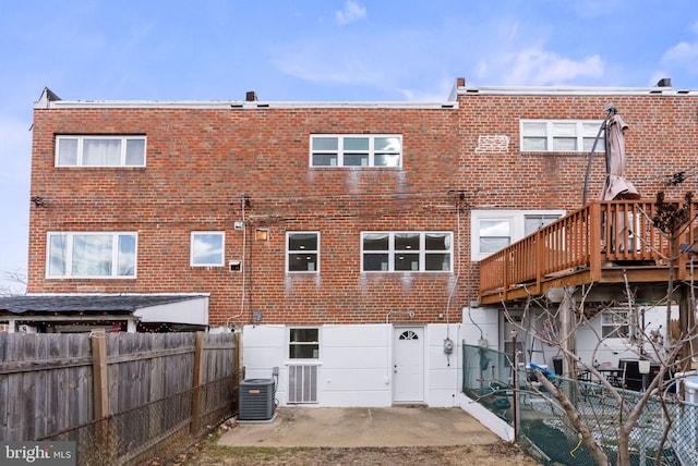 rear view of house featuring central AC unit, a fenced backyard, brick siding, a wooden deck, and a patio area