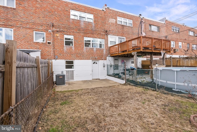 back of house featuring brick siding, a patio, a community pool, a fenced backyard, and a wooden deck