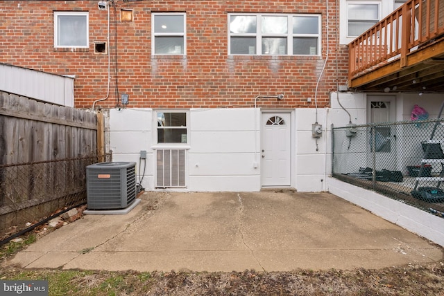 exterior space with a fenced backyard, a patio, cooling unit, and brick siding