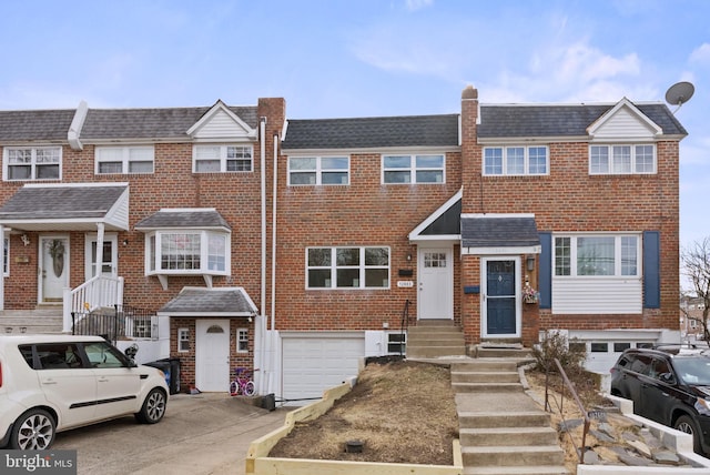 view of property featuring entry steps, driveway, a garage, and brick siding