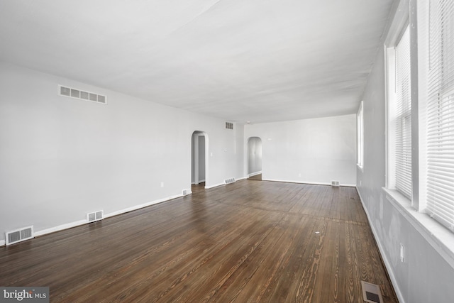 interior space with arched walkways, visible vents, and dark wood finished floors