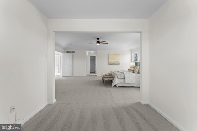 interior space featuring baseboards, ceiling fan, visible vents, and light colored carpet