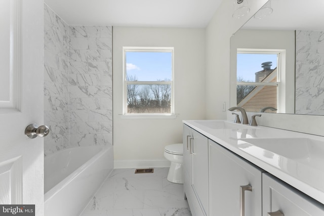 bathroom featuring marble finish floor, double vanity, toilet, a sink, and baseboards