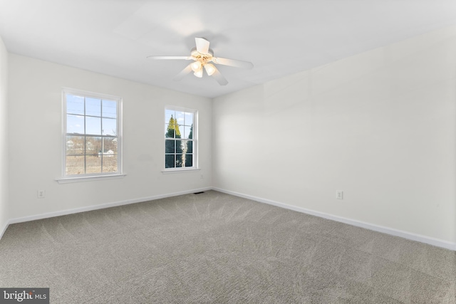 carpeted empty room featuring a ceiling fan and baseboards