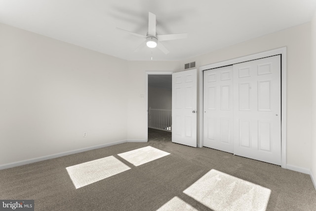 unfurnished bedroom featuring ceiling fan, visible vents, baseboards, a closet, and dark colored carpet