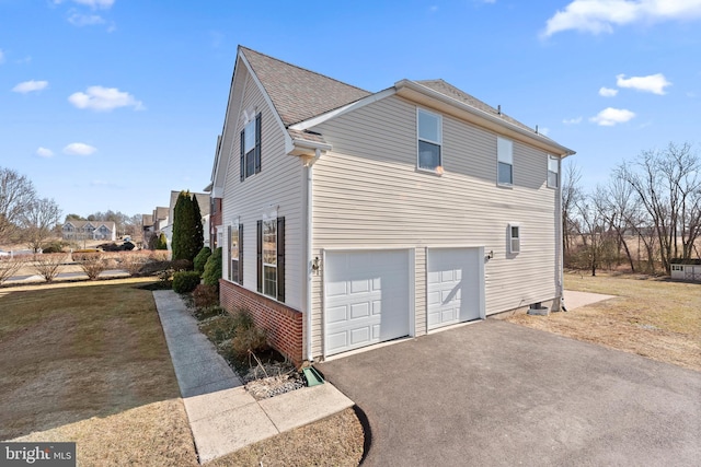 view of home's exterior featuring a garage, brick siding, driveway, and roof with shingles