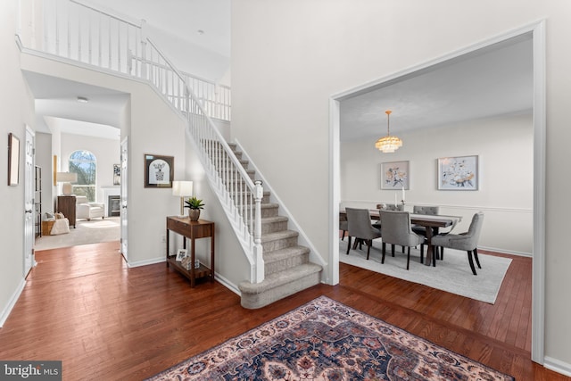 foyer featuring a high ceiling, stairway, dark wood finished floors, and baseboards