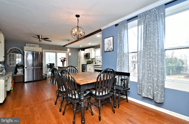 dining area with ceiling fan with notable chandelier, baseboards, wood finished floors, and ornamental molding