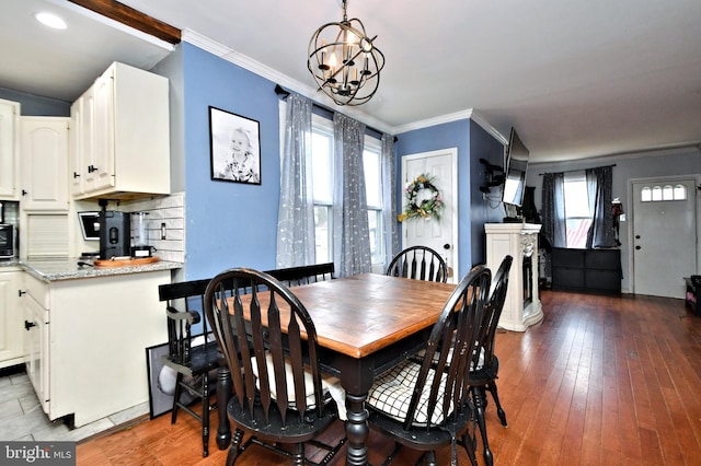 dining area with a notable chandelier, wood-type flooring, and crown molding