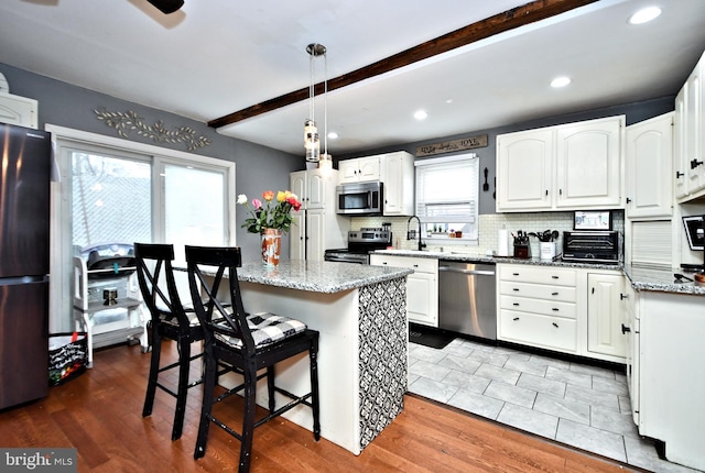 kitchen with stainless steel appliances, light stone counters, and white cabinets