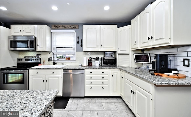 kitchen featuring appliances with stainless steel finishes, white cabinets, and light stone counters