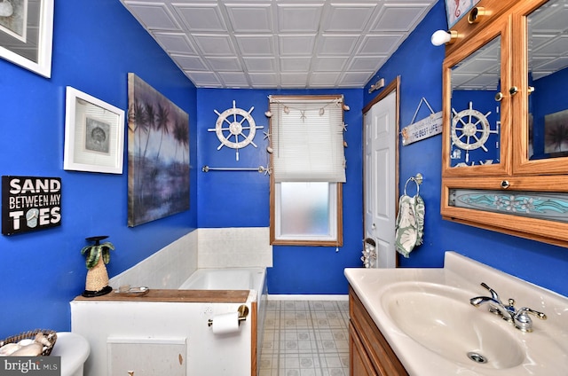 bathroom featuring an ornate ceiling, a garden tub, vanity, and baseboards