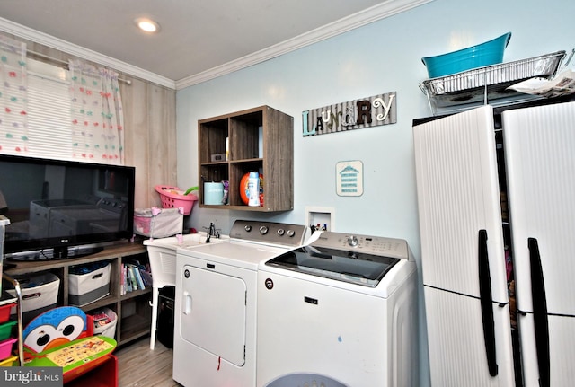 laundry area with laundry area, ornamental molding, independent washer and dryer, light wood-style floors, and a sink