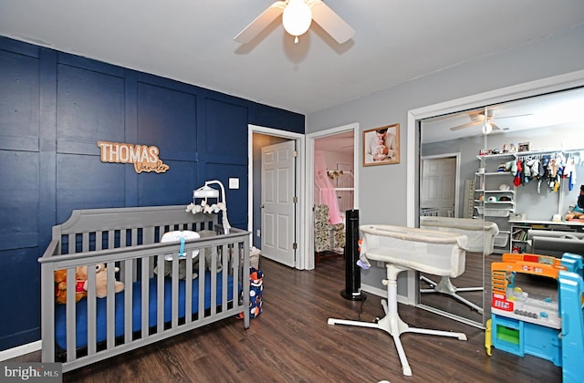 bedroom featuring dark wood-type flooring, a nursery area, a closet, and ceiling fan