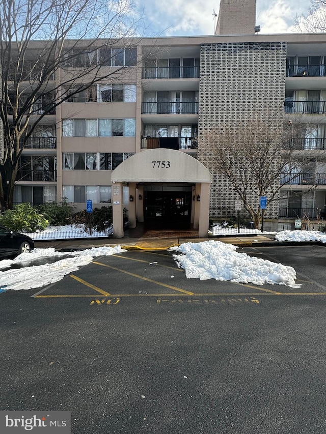 snow covered property with uncovered parking