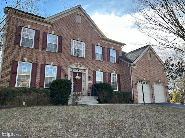 colonial-style house featuring an attached garage, aphalt driveway, and brick siding