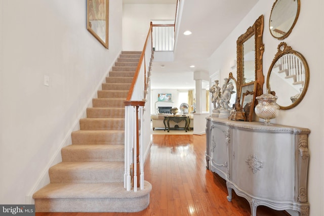 foyer entrance featuring ornate columns, wood-type flooring, stairs, and recessed lighting