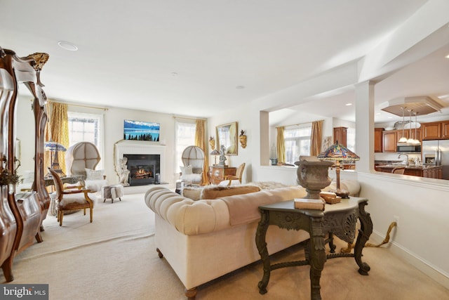 living room with a glass covered fireplace and light colored carpet