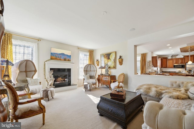 living room with light carpet, a glass covered fireplace, and recessed lighting