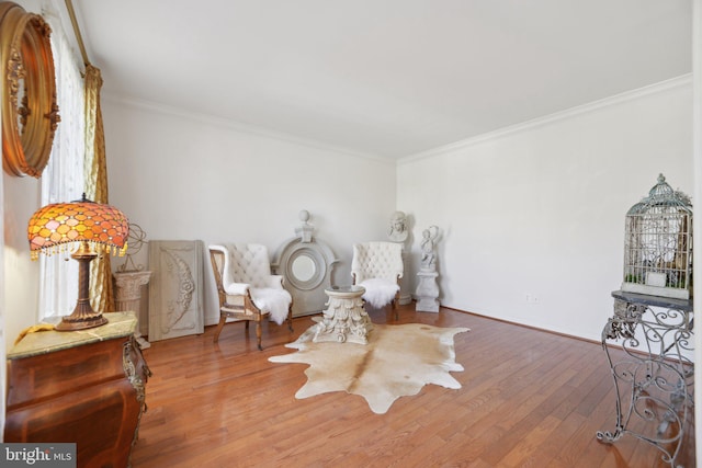 sitting room featuring baseboards, wood finished floors, and crown molding