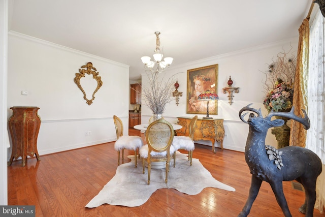 dining space with ornamental molding, visible vents, a notable chandelier, and light wood-style flooring