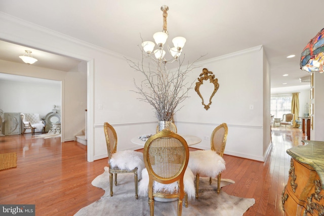 dining room featuring a notable chandelier, stairs, light wood-style flooring, and crown molding