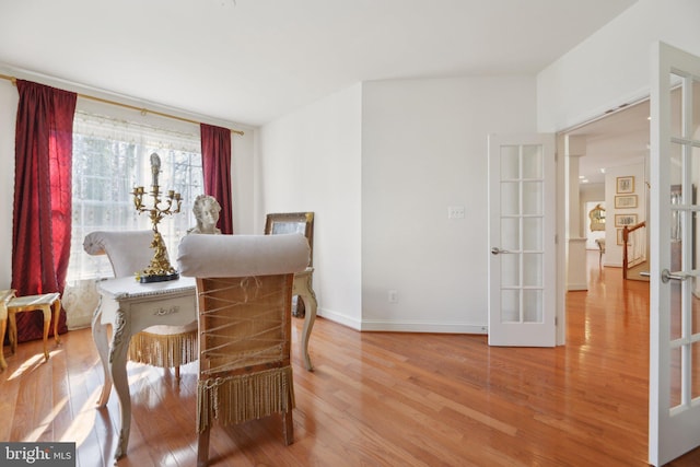 dining area featuring french doors, light wood-style flooring, and baseboards