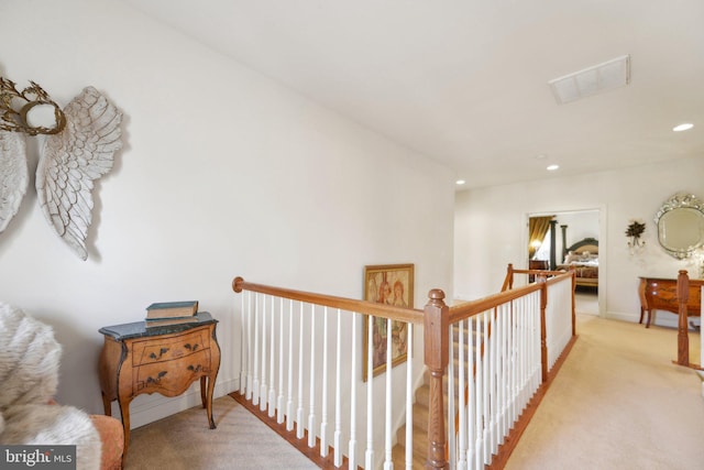 corridor featuring light carpet, an upstairs landing, visible vents, and recessed lighting