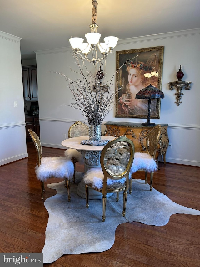 dining room featuring ornamental molding, dark wood-type flooring, a notable chandelier, and baseboards