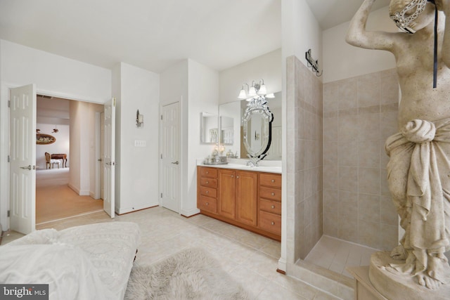 bathroom featuring tile patterned flooring, connected bathroom, vanity, baseboards, and a tile shower