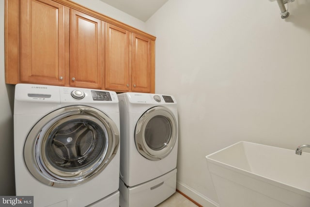 laundry area featuring washing machine and dryer, a sink, cabinet space, and baseboards