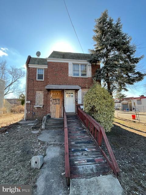 view of front facade featuring brick siding and fence