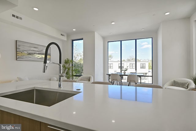 kitchen featuring recessed lighting, a sink, visible vents, open floor plan, and light countertops