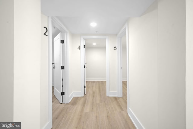 corridor featuring light wood-type flooring and baseboards