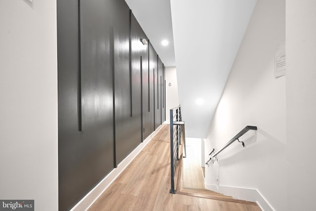 corridor with recessed lighting, baseboards, light wood finished floors, and an upstairs landing