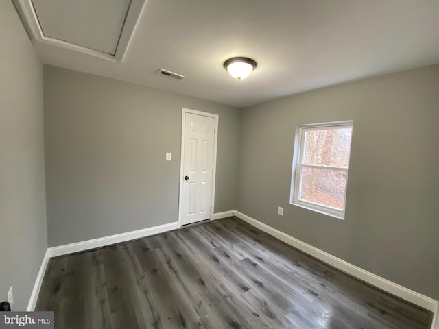 empty room with wood finished floors, visible vents, and baseboards