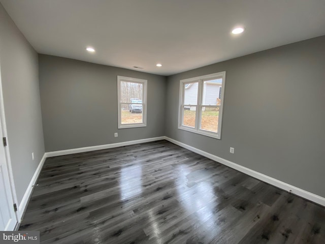 empty room featuring dark wood-type flooring, recessed lighting, visible vents, and baseboards