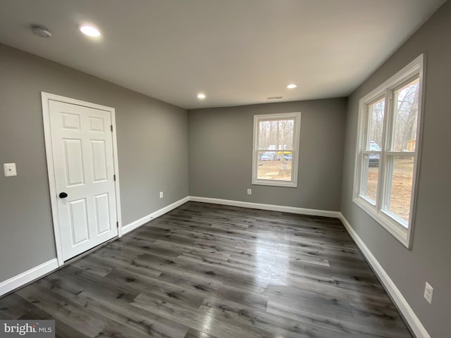 empty room with recessed lighting, dark wood-style flooring, visible vents, and baseboards