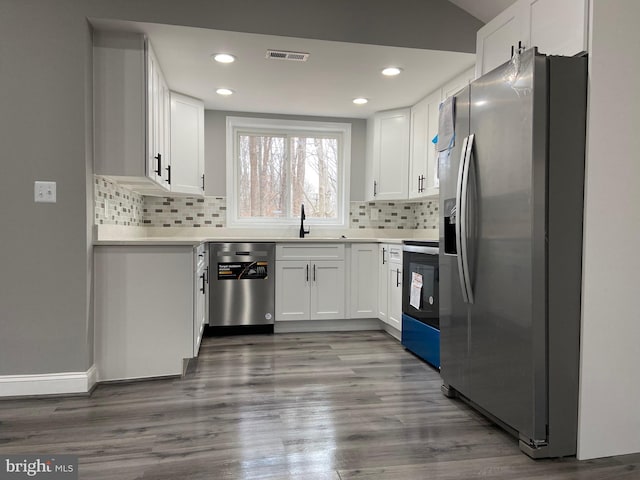 kitchen featuring stainless steel appliances, light countertops, white cabinetry, a sink, and wood finished floors