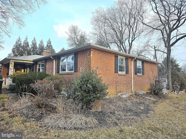 view of side of home featuring a chimney and brick siding