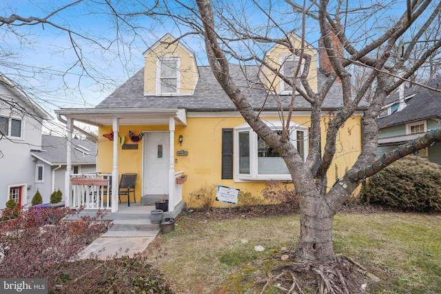 view of front of property featuring a shingled roof, a front yard, and stucco siding