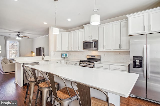 kitchen with white cabinets, appliances with stainless steel finishes, light countertops, and decorative light fixtures