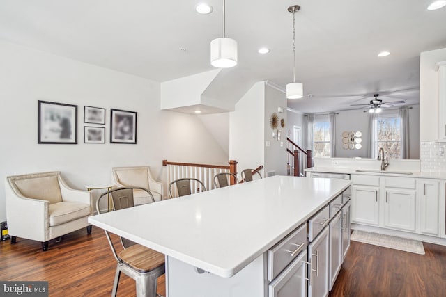 kitchen featuring a kitchen breakfast bar, open floor plan, decorative light fixtures, light countertops, and a sink