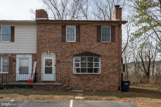 view of front facade featuring a chimney and brick siding