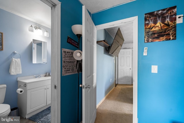 bathroom with toilet, a textured ceiling, vanity, and baseboards