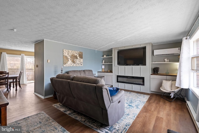 living room featuring a wall unit AC, a textured ceiling, wood finished floors, and a glass covered fireplace