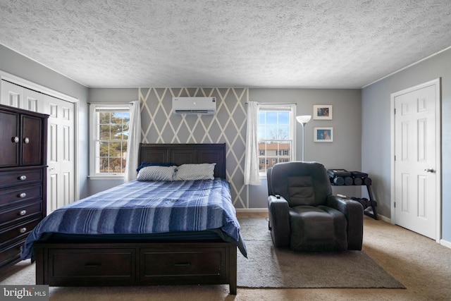 bedroom featuring light carpet, wallpapered walls, baseboards, a textured ceiling, and an AC wall unit