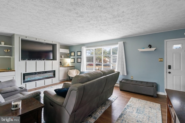 living area featuring a glass covered fireplace, an AC wall unit, a textured ceiling, and wood finished floors