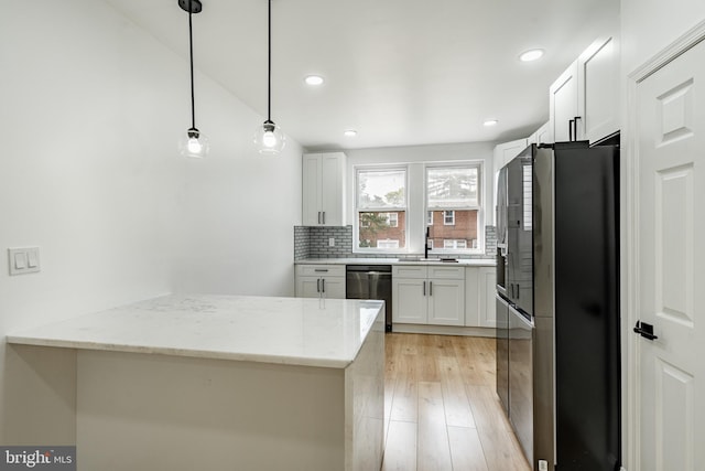 kitchen featuring white cabinets, dishwasher, light stone counters, freestanding refrigerator, and pendant lighting