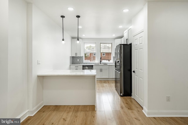 kitchen featuring tasteful backsplash, white cabinets, black fridge with ice dispenser, a peninsula, and stainless steel dishwasher